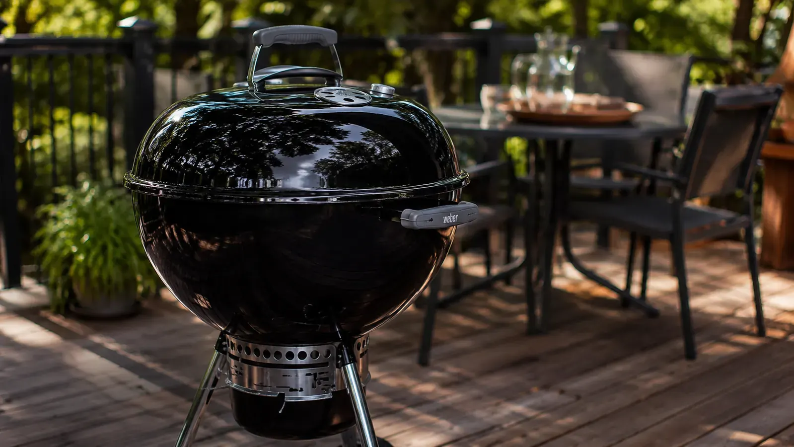 Weber 22-inch kettle charcoal grill sitting assembled on a concrete patio, lid closed, early morning light